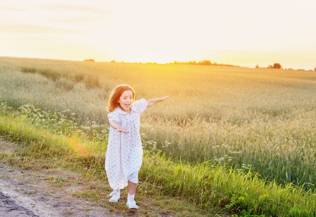 Beautiful little girl on background field  at sunset