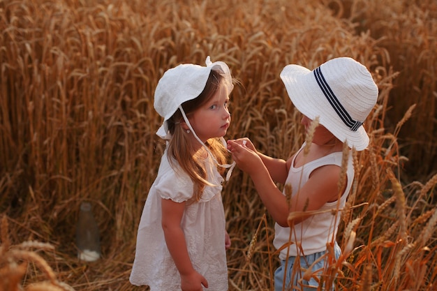 a beautiful little girl in a blue dress and a yellow hat is standing in a field with flowers