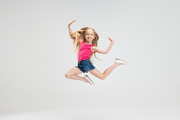 Photo beautiful little girl in casual clothes jumping isolated on white studio background happy childhood concept