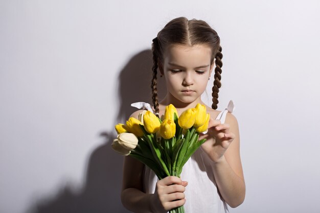 Beautiful little girl caucasian with a bouquet of tulips