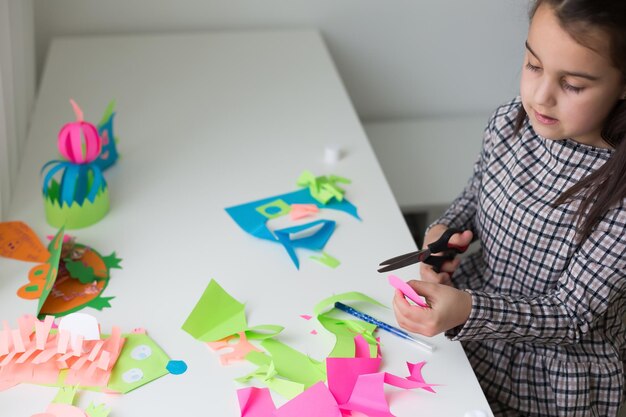 Bella bambina che taglia la carta con le forbici durante la lezione di arte. concetto di educazione dei bambini. lavoretti per bambini.ritorno a scuola