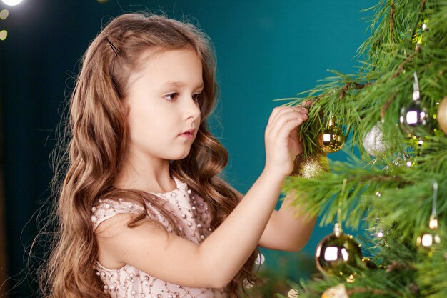 Beautiful little girl decorating  Christmas tree at home