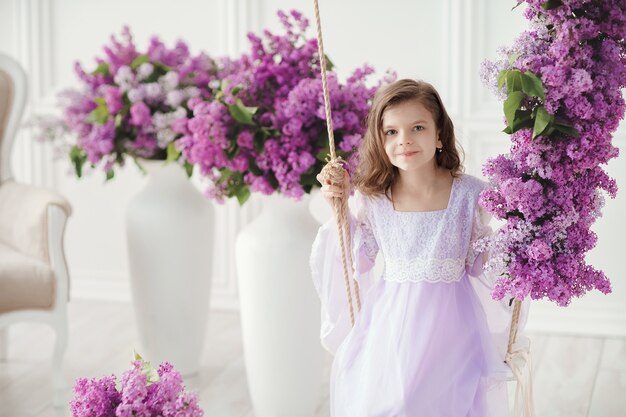 Beautiful little girl in a delicate dress with flowers of lilac