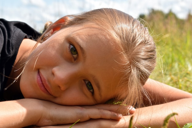 Beautiful little girl in a green grass on summer