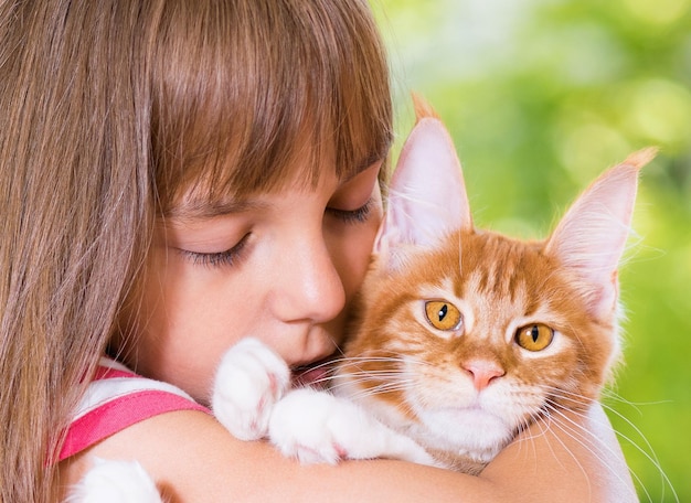 Foto bella bambina che tiene il gattino rosso sveglio del maine coon