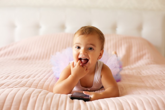 a beautiful little girl is lying on the bed with a pink blanket with a phon