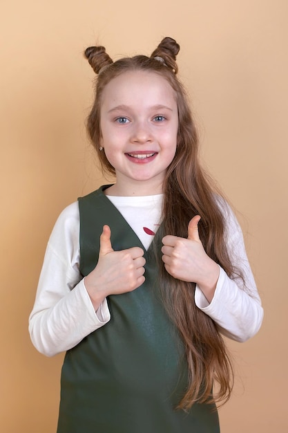 A beautiful little girl in a long sleeve shirt on a beige background shows emotions Provocation and rude attitude resentment fear