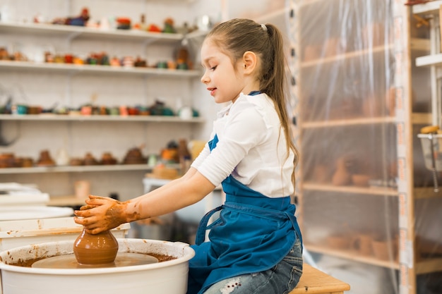 beautiful little girl making a pot of clay in a pottery workshop