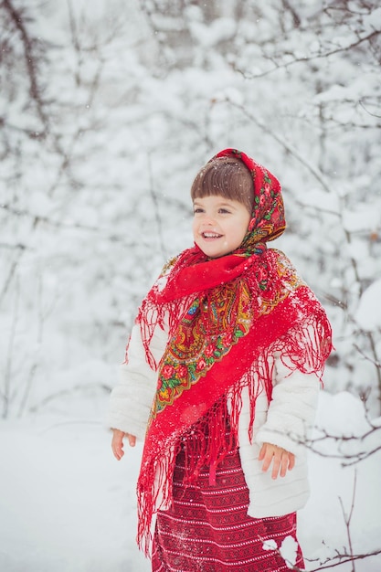 Beautiful little girl in old Russian clothes in a winter forest