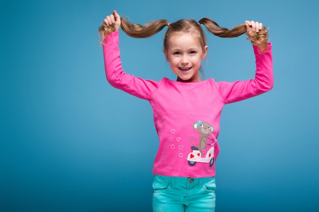 Foto bella bambina in camicia rosa con scimmia e pantaloni blu