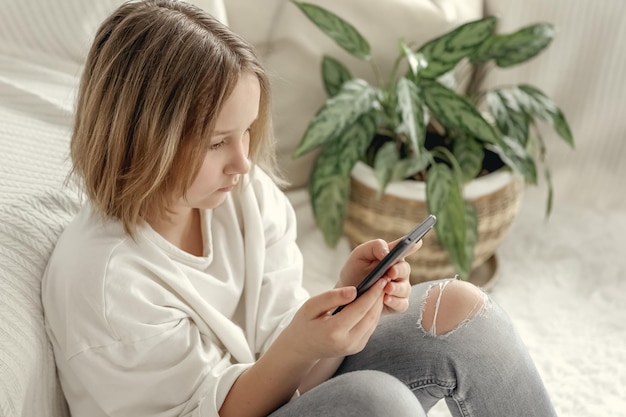 Beautiful little girl playing game or watching video on smartphone mobile Girl watching cartoons or browsing internet Portrait of little girl using smartphone while sitting