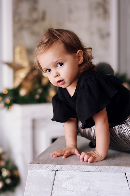 Beautiful little girl playing near Christmas tree at home