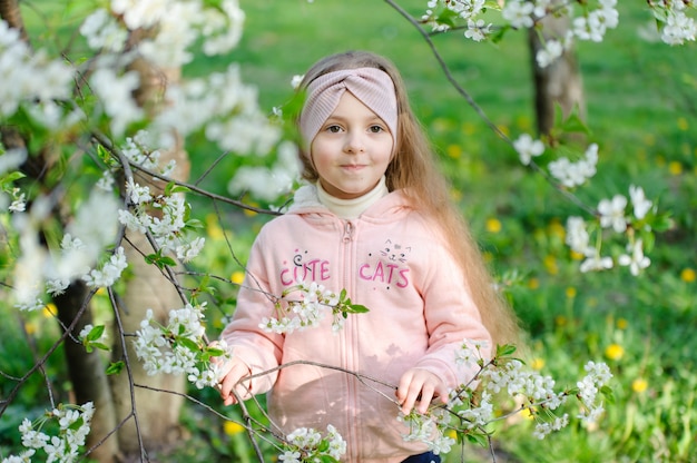 Beautiful little girl portrait near a blossoming cherry tree.