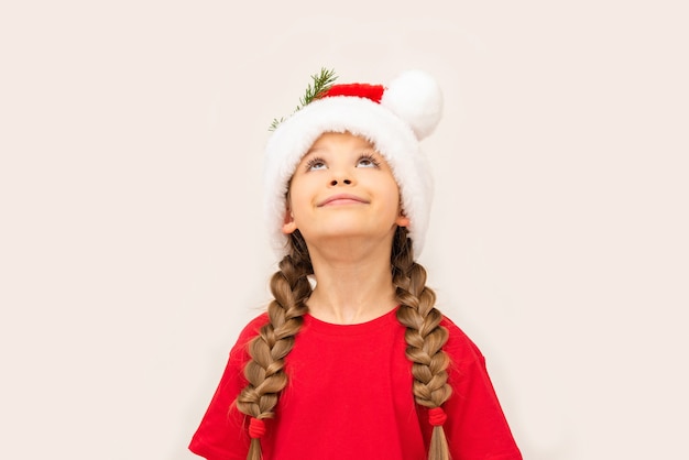 Beautiful little girl posing in a red t-shirt and Christmas hat.