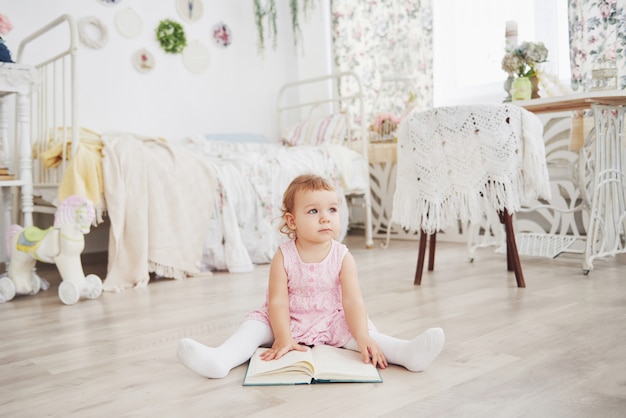 Beautiful little girl read book with her favorite bear on a soft plush blanket