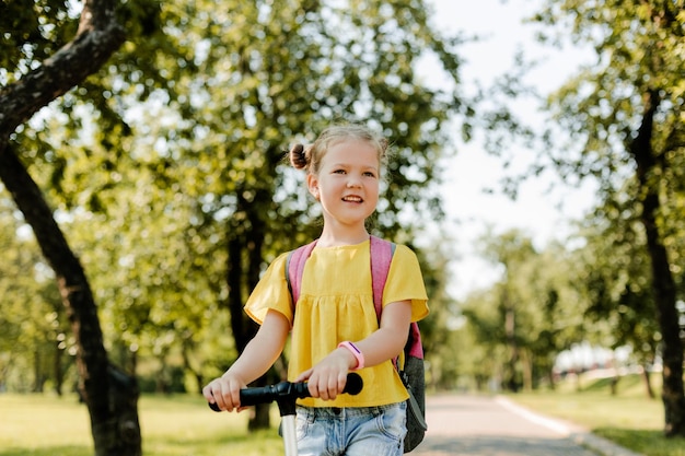 Foto una bella ragazzina guida uno scooter mentre torna a scuola