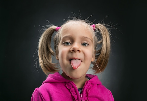 Photo beautiful little girl showing her tongue