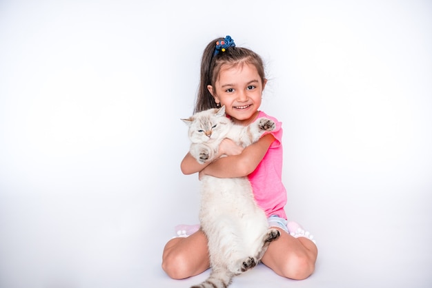 Beautiful little girl sitting on the floor with a fluffy cat A child with an animal