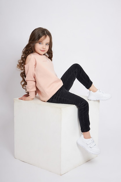 Beautiful little girl smiles, child in autumn clothes poses on a white background