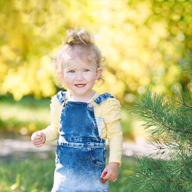 Beautiful little girl smiling Look not at the camera Park outside the house Advertising photo Positive child after quarantine End lockdown