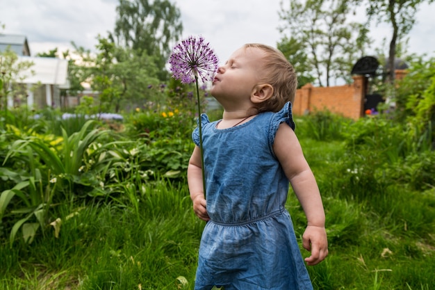 Beautiful little girl sniffing flower in the garden