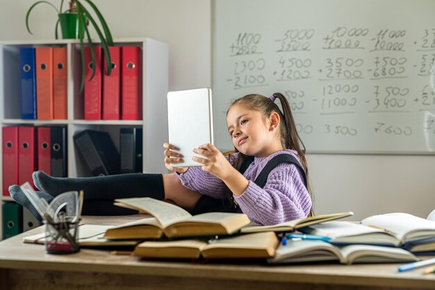 Beautiful little girl studying in distance learning and communicating through tablet