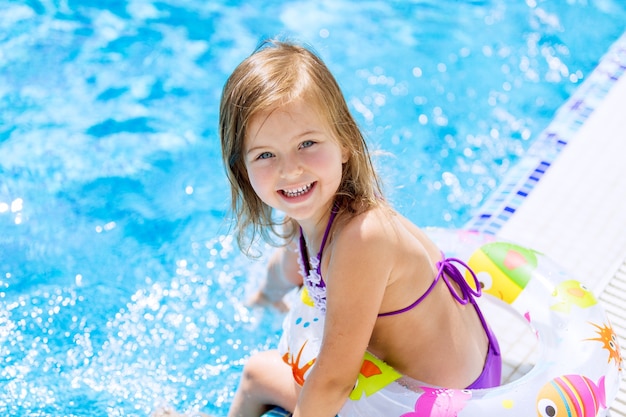 Красивая маленькая девочка, загорая в бассейне
