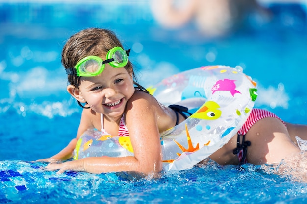 Beautiful little girl swimming at the pool