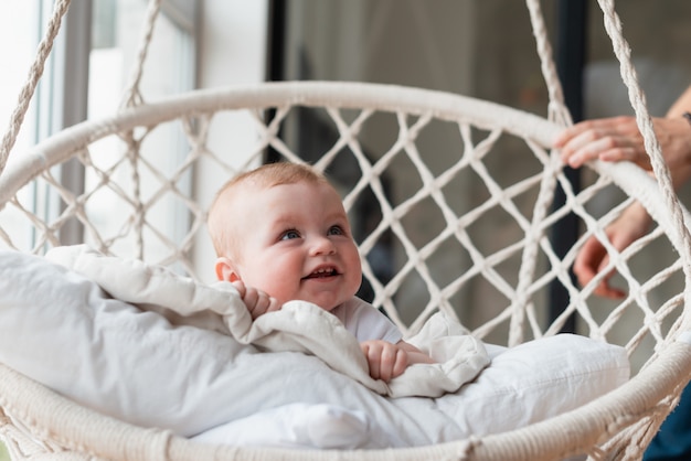 Beautiful little girl swinging in a hanging chair