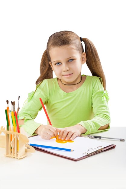 Beautiful little girl at the table with pencil isolated