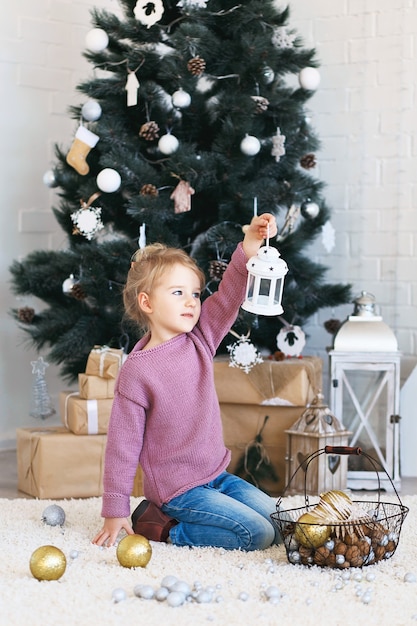 Bella bambina in attesa di un miracolo nelle decorazioni natalizie