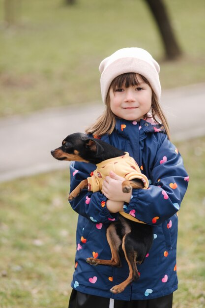 Beautiful little girl walk with cute dog outdoors six year old girl hug her pet