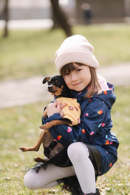 美しい小さな女の子がかわいい犬と一緒に屋外で歩く6歳の女の子が彼女のペットを抱きしめます