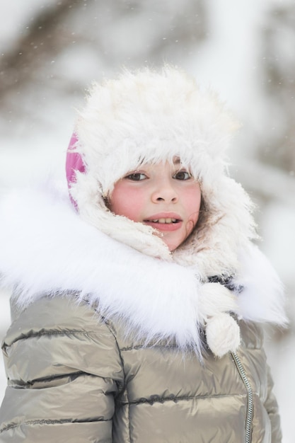 Beautiful little girl in warm jacket in winter forest