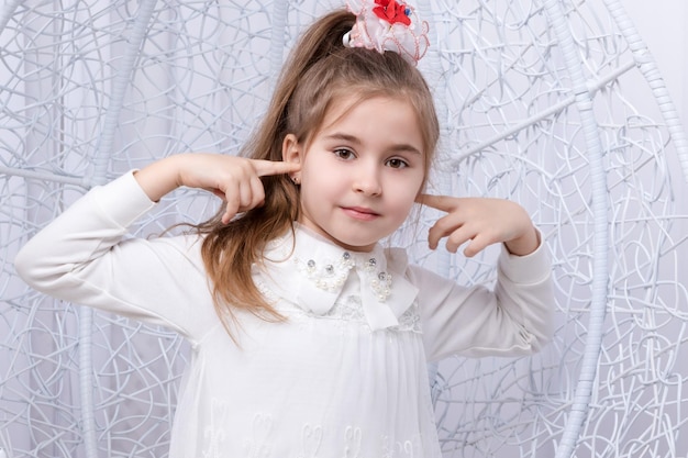 Beautiful little girl in a white dress covered her forefingers their ears