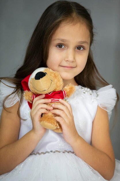 Beautiful little girl in a white dress with a toy