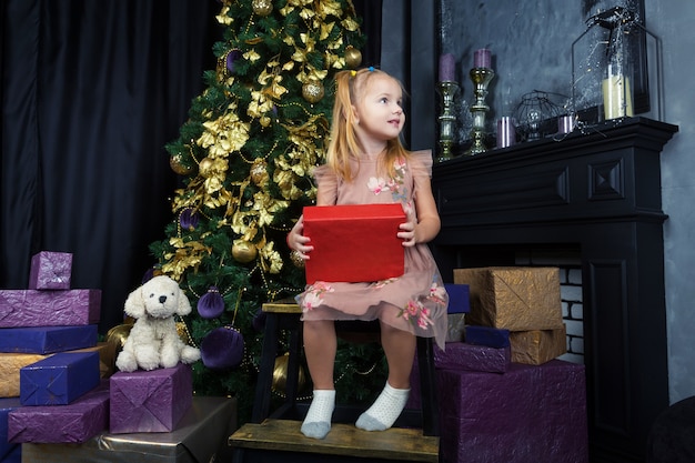 Красивая маленькая девочка с голубыми глазами хранит свой подарок в комнате