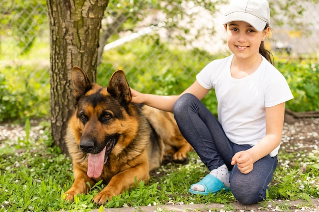 beautiful little girl with a german shepherd playing on the lawn at the day time.