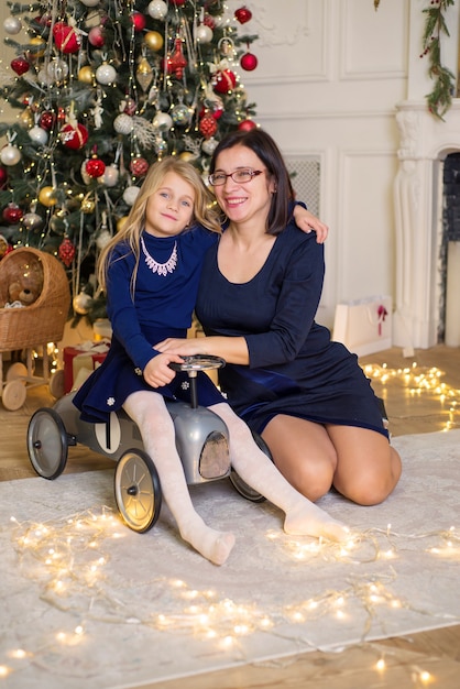 beautiful little girl with mom in christmas near the christmas tree