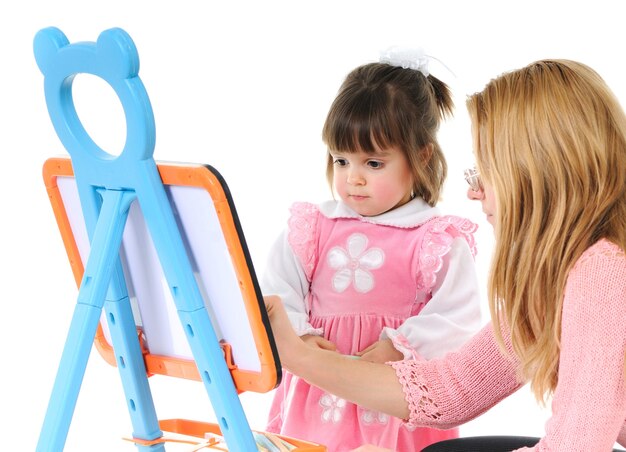 Beautiful little girl with mom draw together on the blackboard