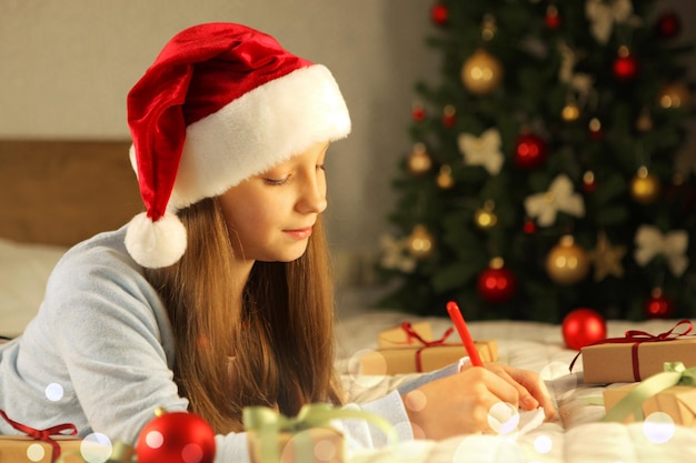 Beautiful little girl writing a letter to santa claus in the christmas interior