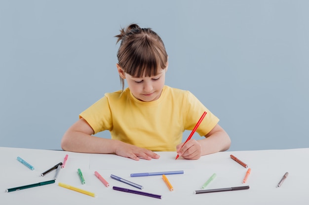 Beautiful little girl in a yellow t-shirt coloring