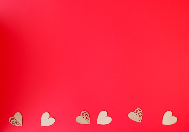 Beautiful little wooden hearts on red background