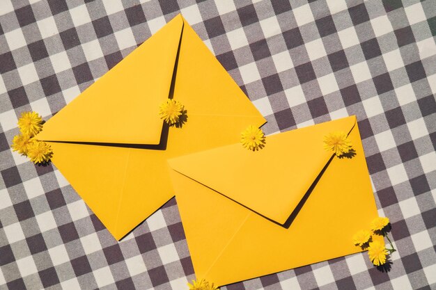 写真 2つの郵便の黄色い封筒に空の紙の紙幣に美しい小さな黄色いカモミールデイジー花