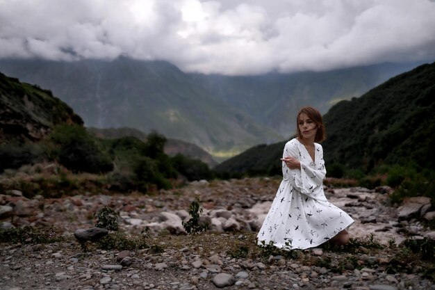 하얀 옷을 입은 아름다운 외로운 여자가 산들 사이에 있다