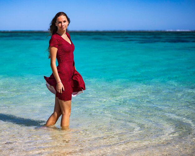 beautiful long-haired girl in a dress soaks her feet in the water in turquoise bay western australia