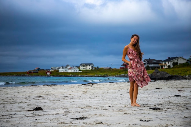 드레스를 입은 아름다운 장발 소녀가 노르웨이의 유명한 람베르그 해변(람베르그스트란다)을 따라 걷는다