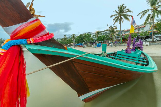 Beautiful long tail boat painted with bright colors moored on the beach