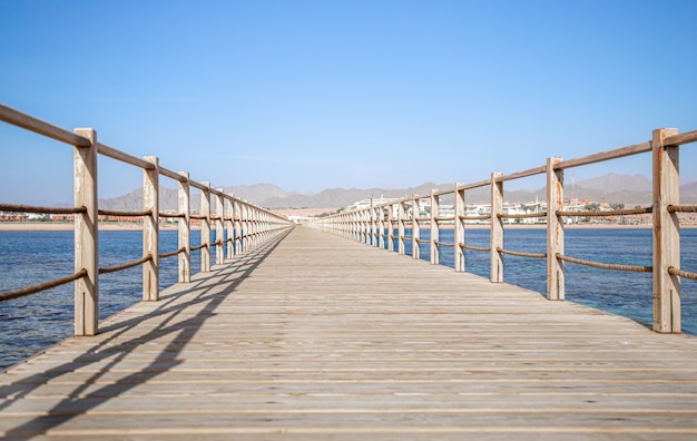 beautiful long wooden pier among the ocean and mountains.