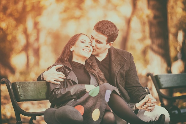 Beautiful in love couple sitting on a bench in autumn park